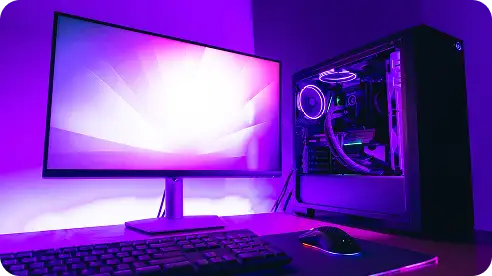 Een strakke computeropstelling bestaat uit een verlichte monitor met een schitterend paars scherm. Naast het toetsenbord en de muis staat een verlichte gaming-pc-behuizing