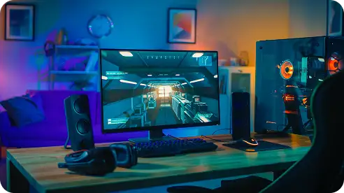 Een gamingopstelling met een monitor waarop het interieur van een ruimteschip te zien is, geflankeerd door luidsprekers. Vlakbij staat een pc-behuizing met oranje oplichtende lampjes. De ruimte is sfeervol verlicht met blauwe en paarse tinten, wat een futuristische, meeslepende sfeer creëert